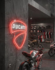 Néon LED mural logo Ducati allumé dans un garage moto, déco motard italien