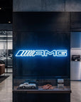 Néon LED mural logo AMG allumé dans un showroom, déco garage voiture sportive