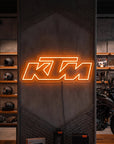 Néon LED mural logo KTM allumé dans un magasin moto, déco garage motard