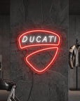 Néon LED mural logo Ducati allumé dans un garage moto, déco motard italien
