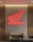 Néon LED mural logo Honda aile allumé dans un salon, déco garage moto