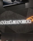 Néon LED mural logo McLaren allumé dans un garage, déco supercar britannique